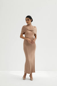 Woman wearing a beige ribbed dress with a draped effect on a white background