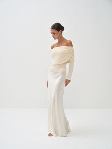Woman wearing a stylish off-shoulder top and skirt on a white background