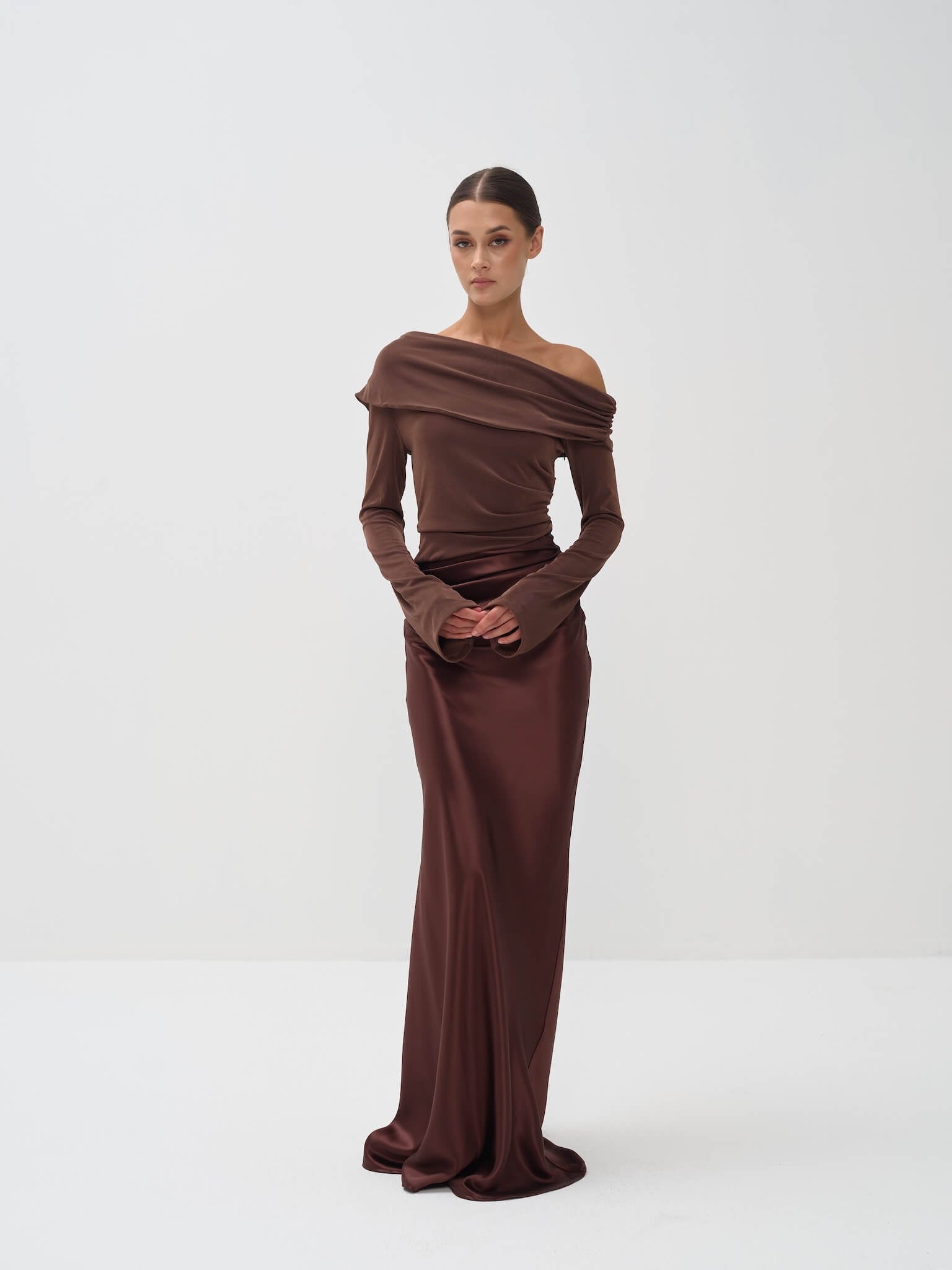 Woman wearing a brown off-shoulder gown on a white background