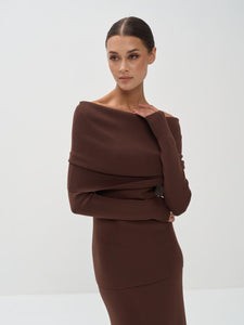 Woman wearing a brown off-shoulder top and skirt set against a white background