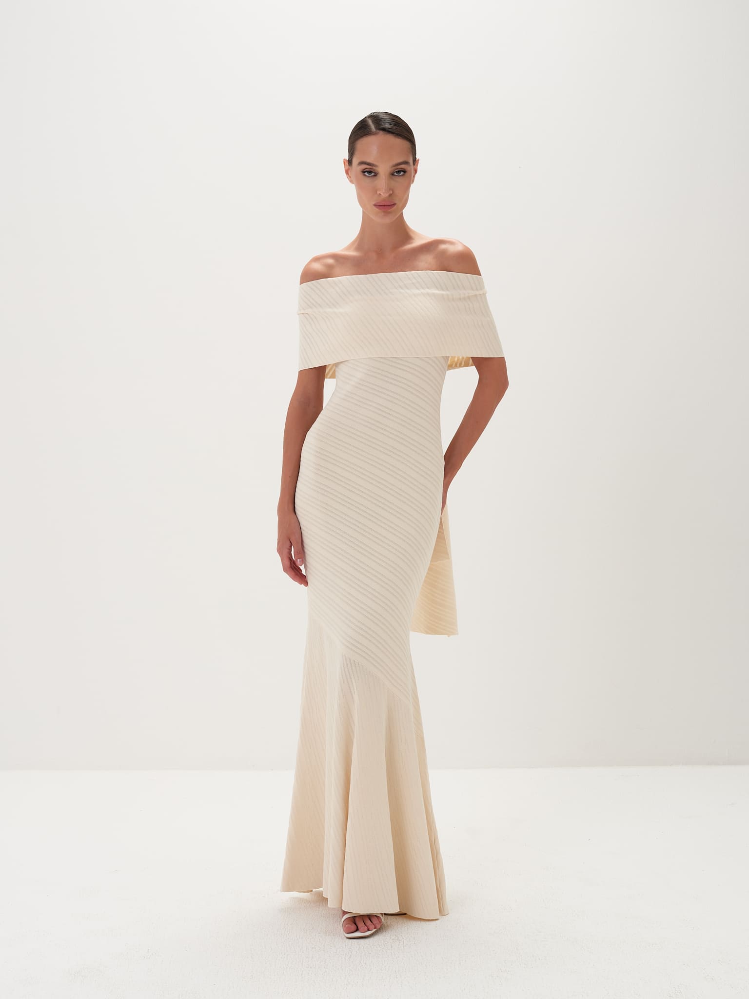 Woman wearing a strapless, off-white evening gown on a white background