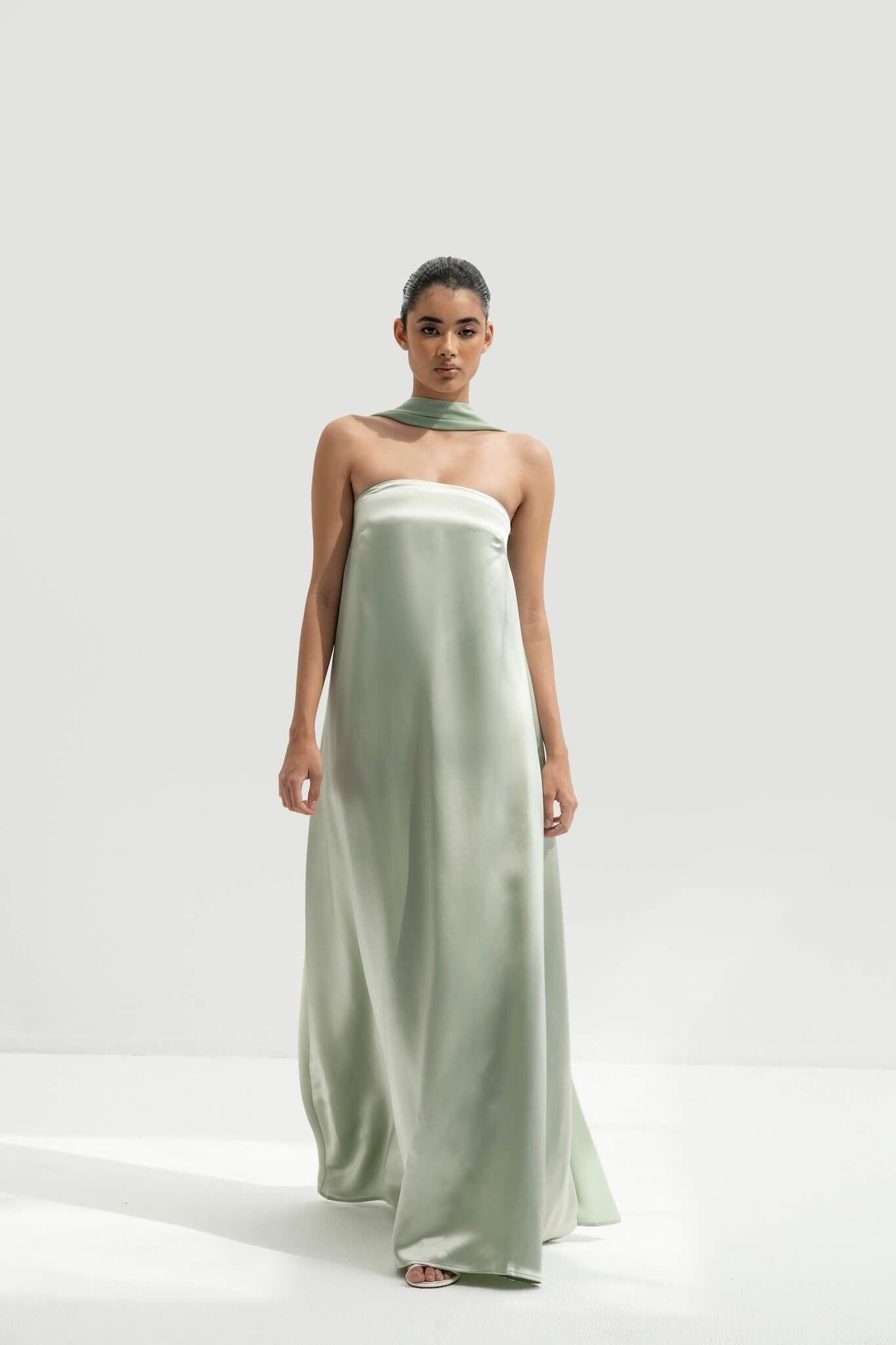 Woman wearing a green halter neck gown on a white background