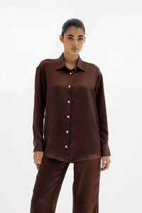 Woman wearing a brown button-up shirt and pants on a white background