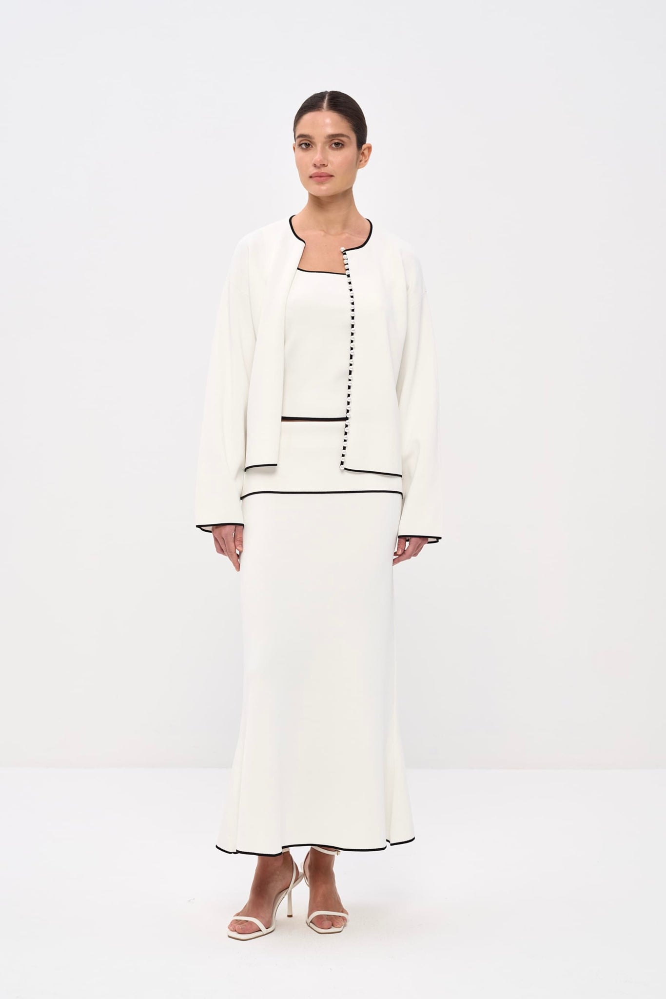 Woman wearing a white outfit with black trim on a white background