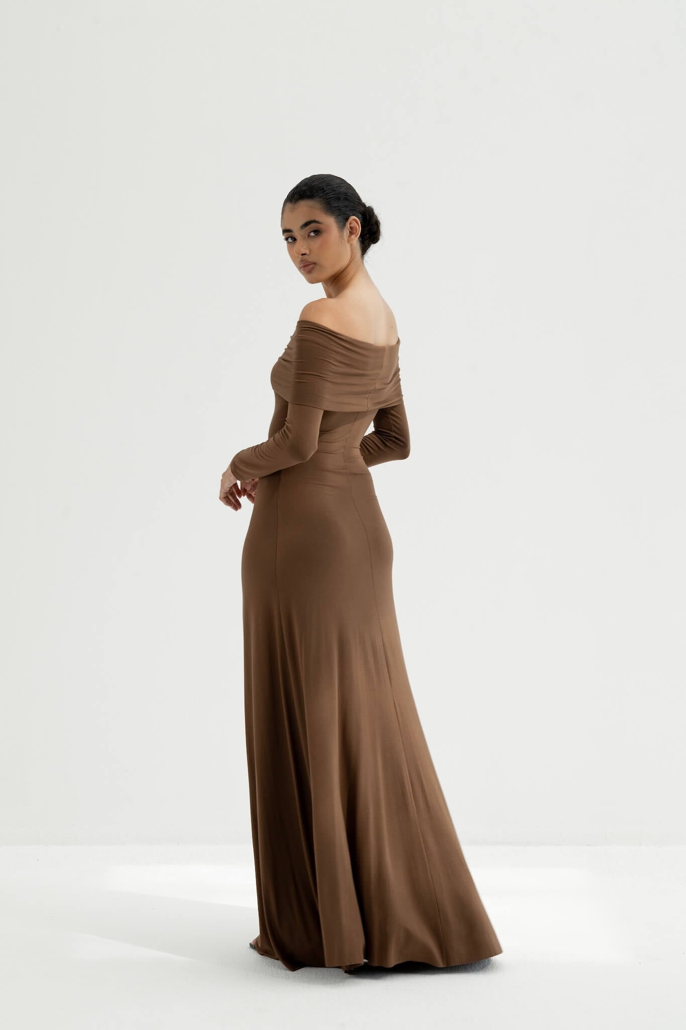 Woman wearing a brown off-shoulder gown on a white background