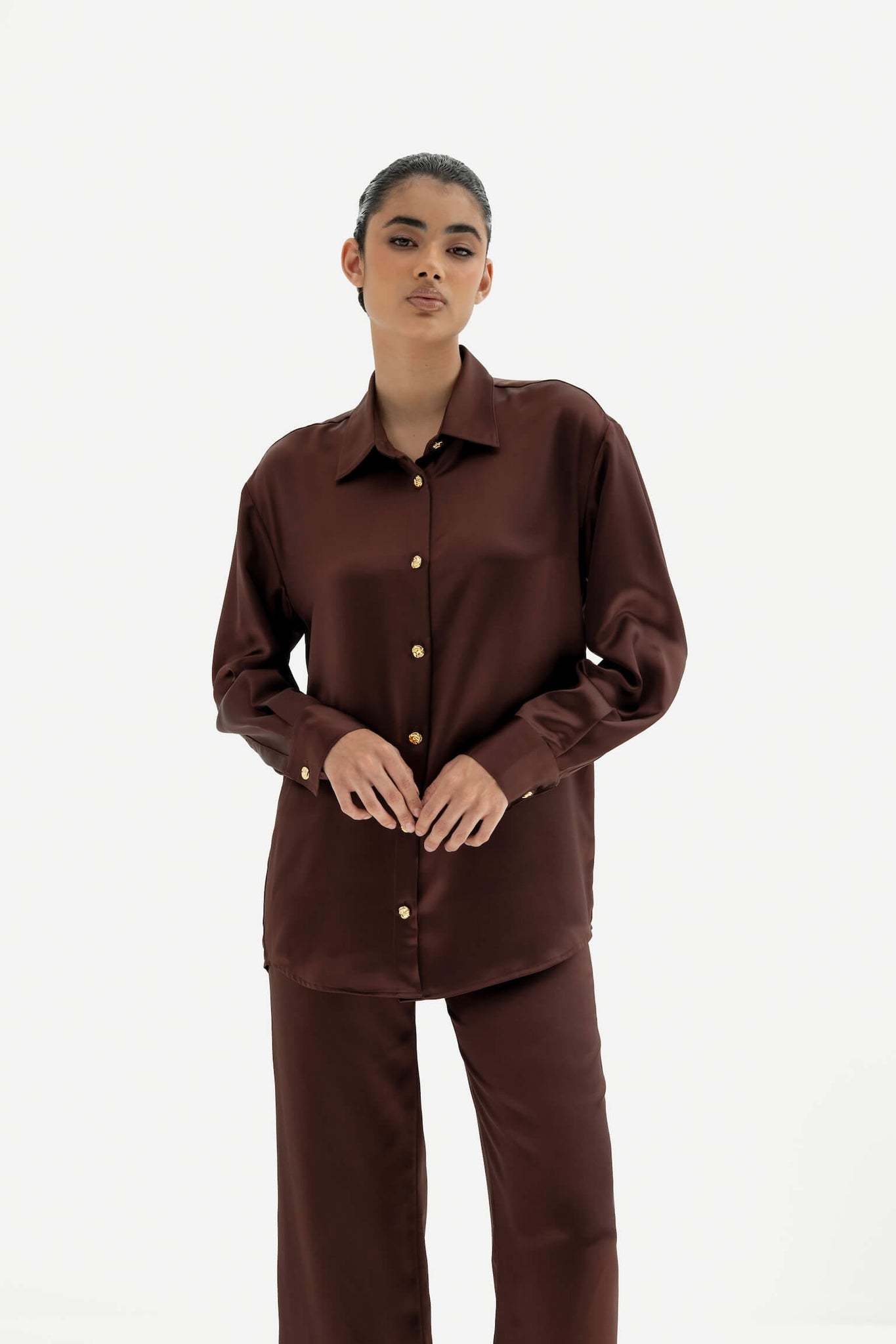 Person wearing a brown shirt and pants set on a white background