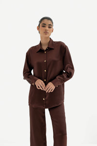Person wearing a brown shirt and pants set on a white background