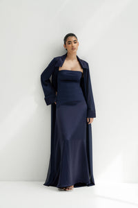 Woman wearing a navy blue strapless gown with a matching long coat against a white background