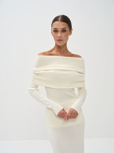 Woman wearing a white off-shoulder dress against a plain background