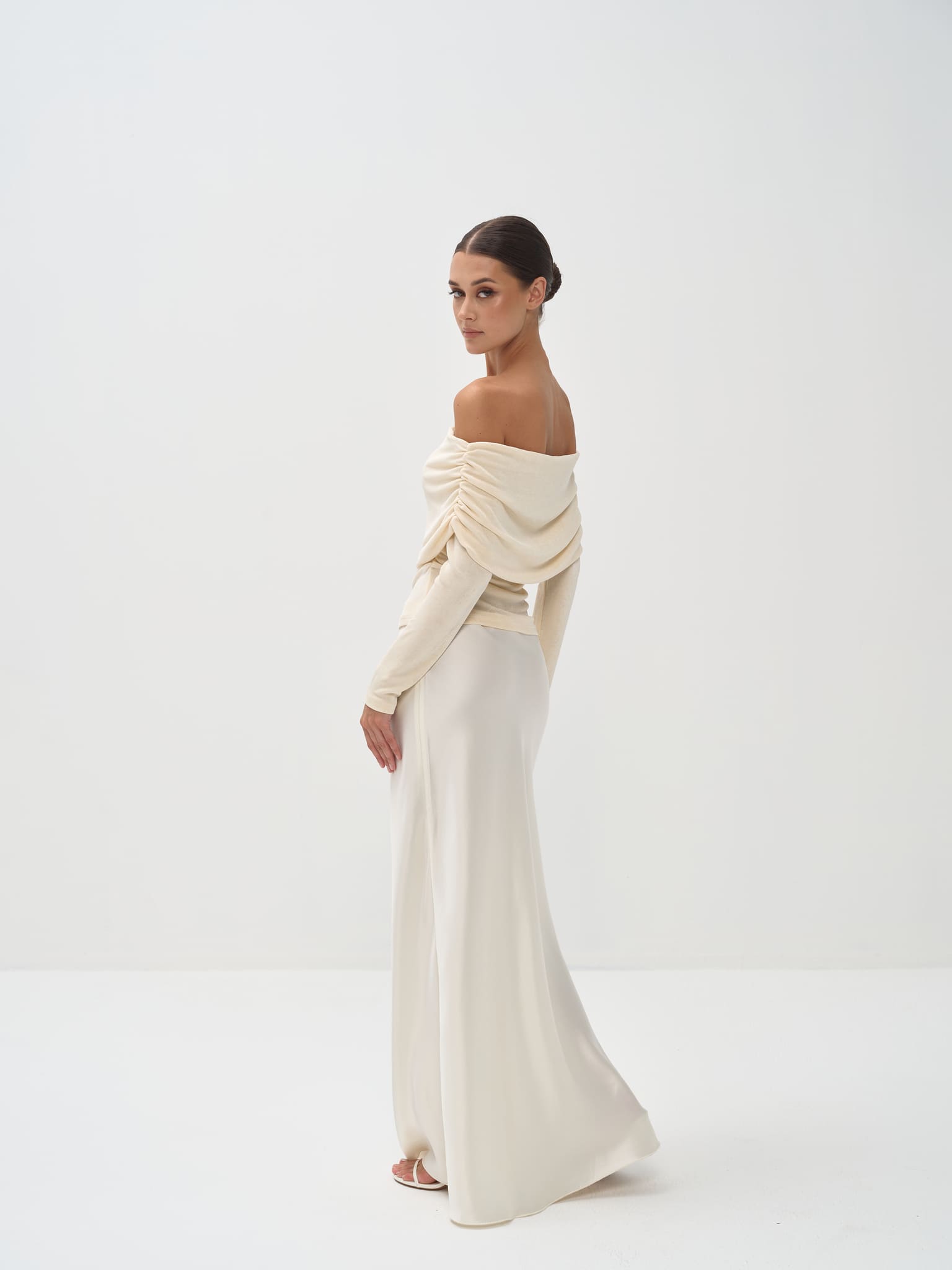 Person wearing a long, light-colored skirt and top on a white background