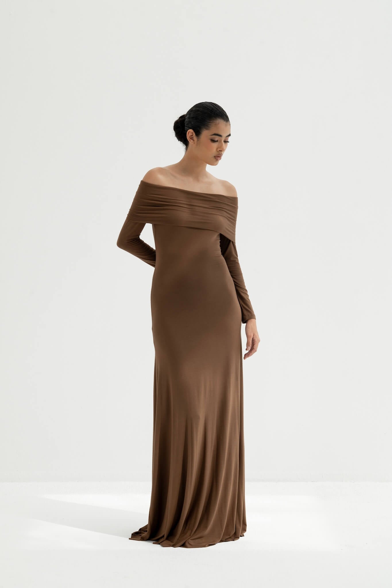 Woman wearing a brown off-shoulder gown on a white background
