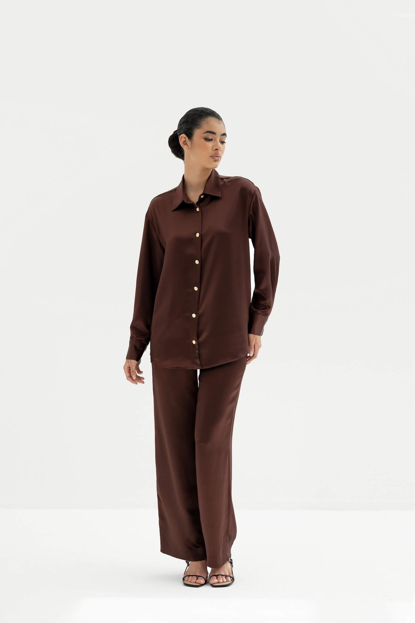 Woman wearing a brown shirt and pants set on a white background