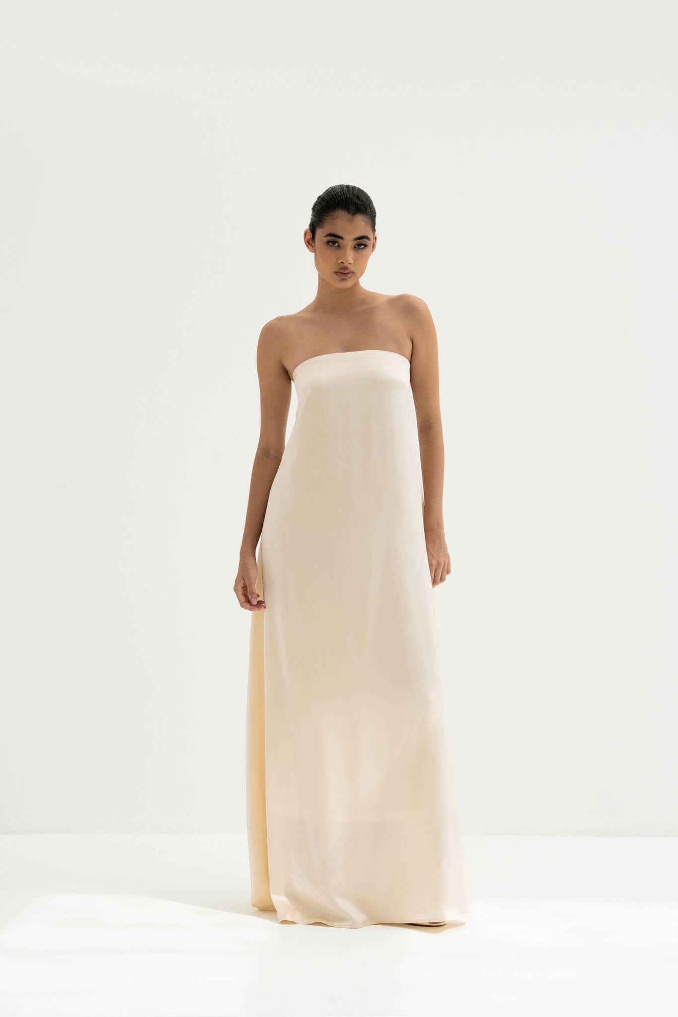 Woman wearing a strapless white gown with a long scarf on a white background
