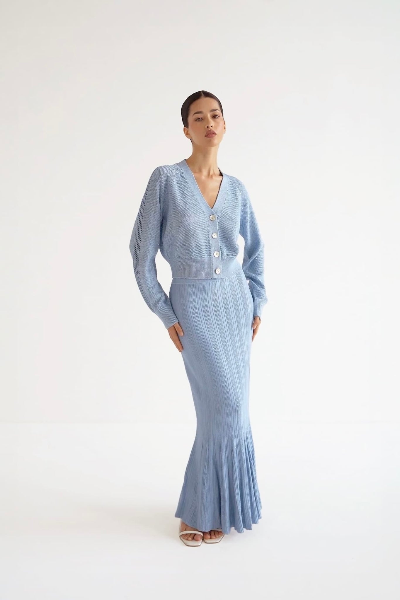 Woman wearing a light blue cardigan and skirt set on a white background