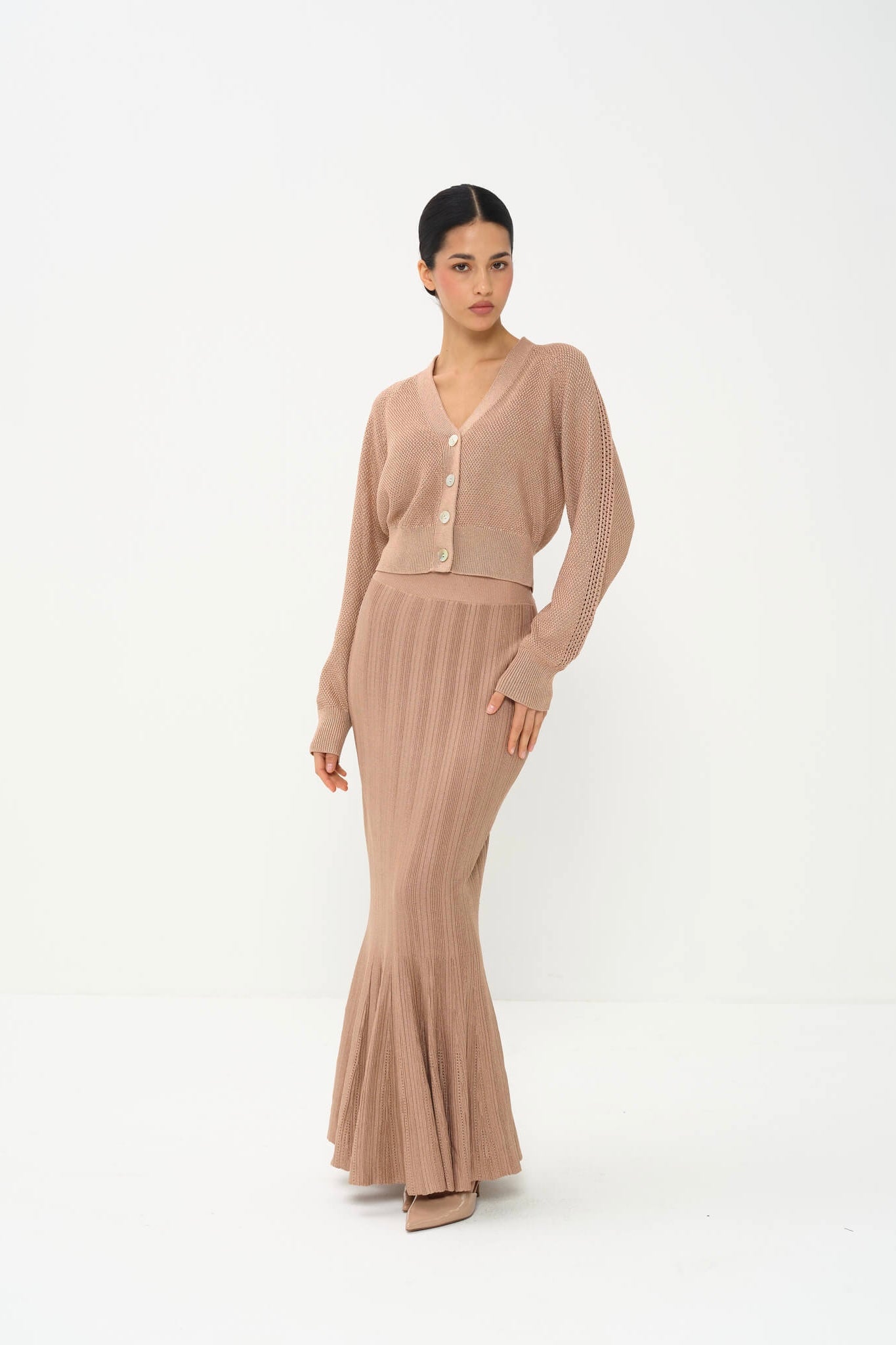 Woman wearing a beige cardigan and long skirt on a white background