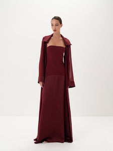 Woman wearing a burgundy dress with matching coat on a white background