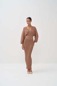 Woman wearing a brown ribbed knit dress on a white background