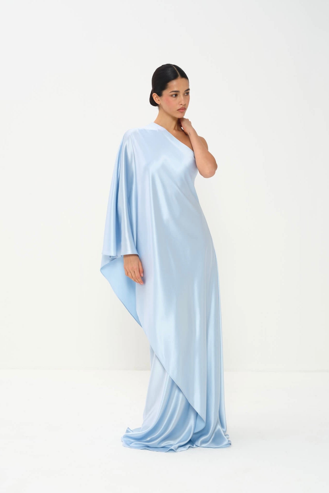 Woman wearing a light blue one-shoulder dress on a white background
