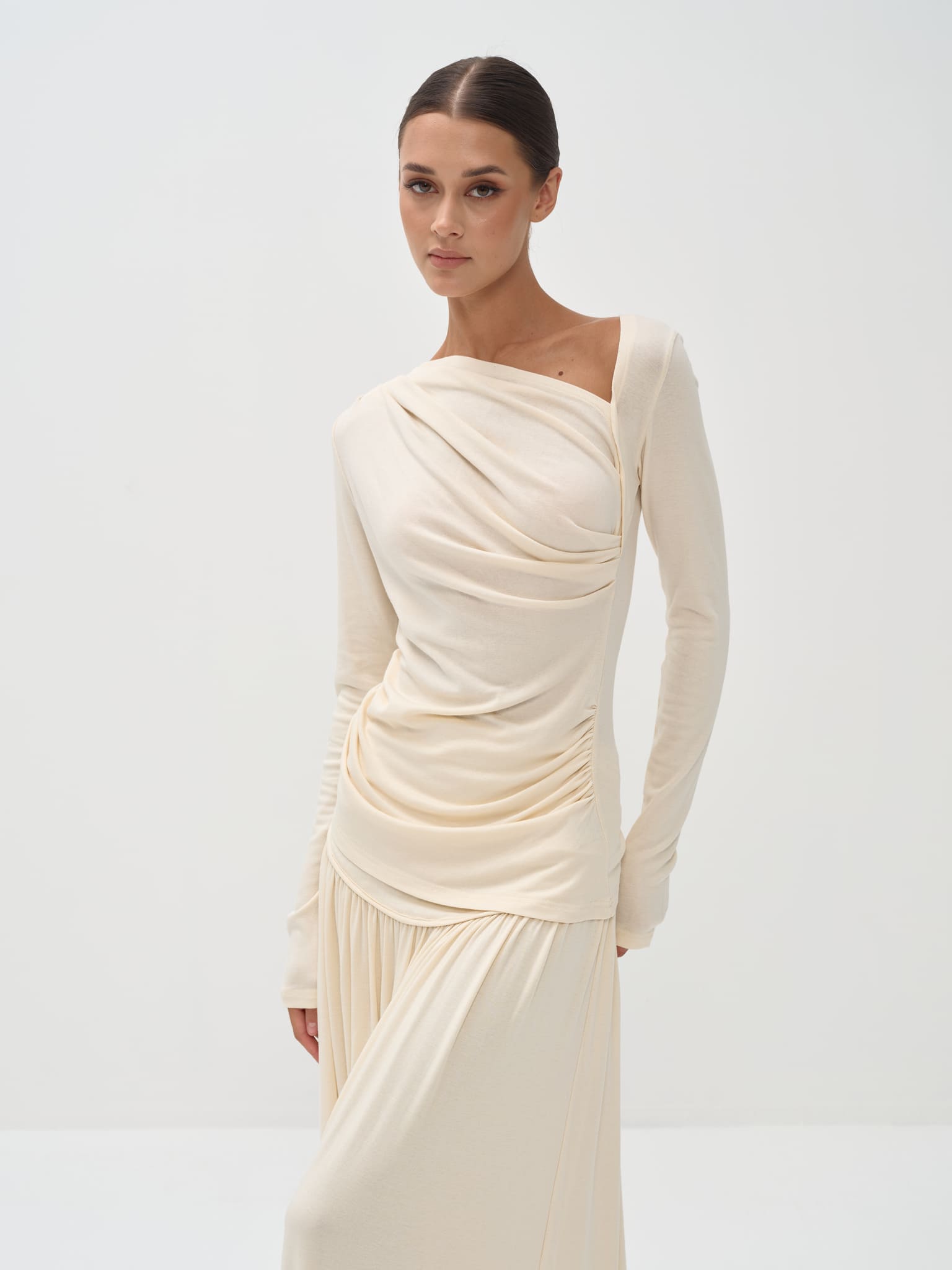 Woman wearing a cream-colored dress with long sleeves on a white background