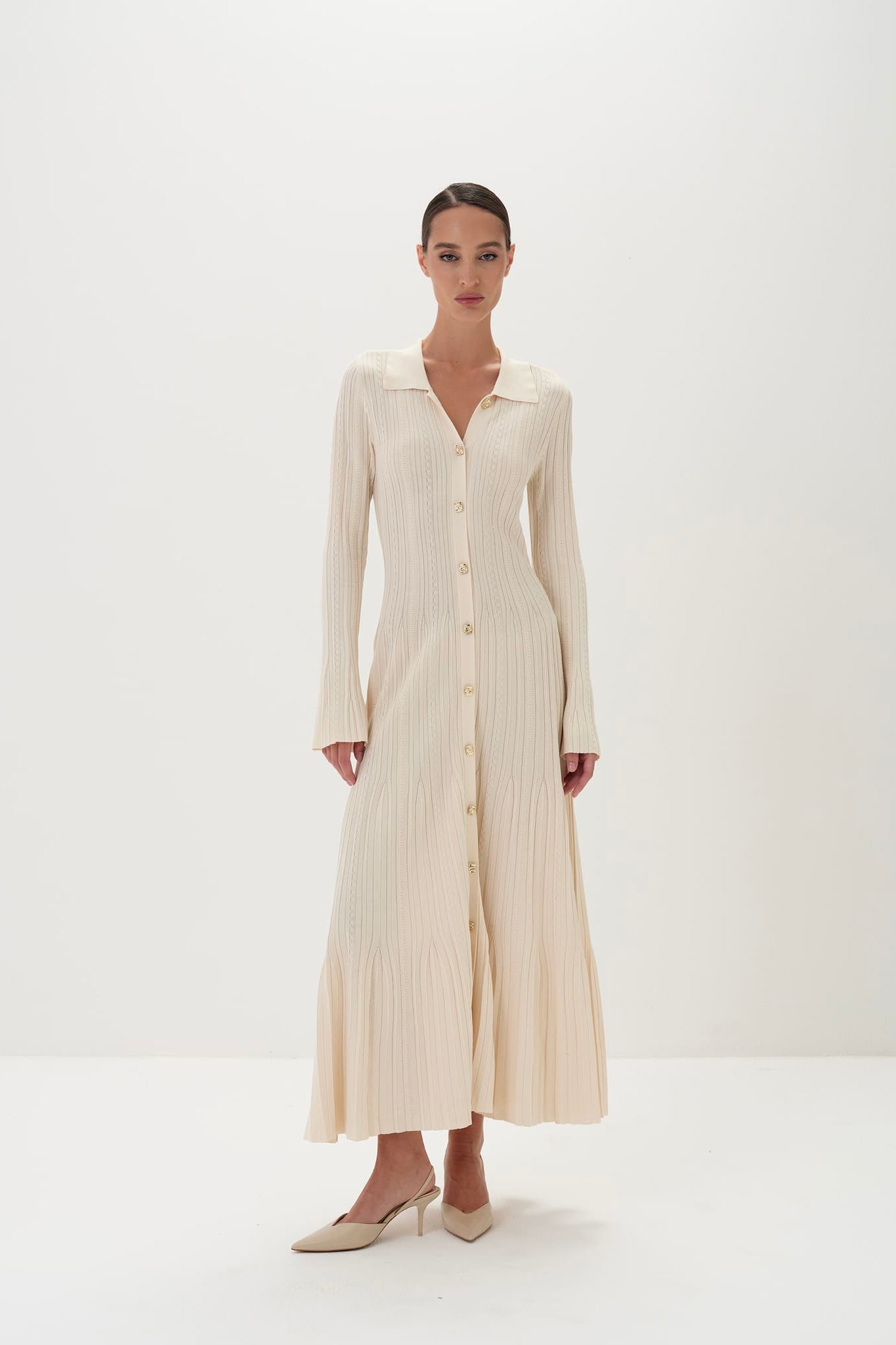 Woman wearing a long beige dress against a white background