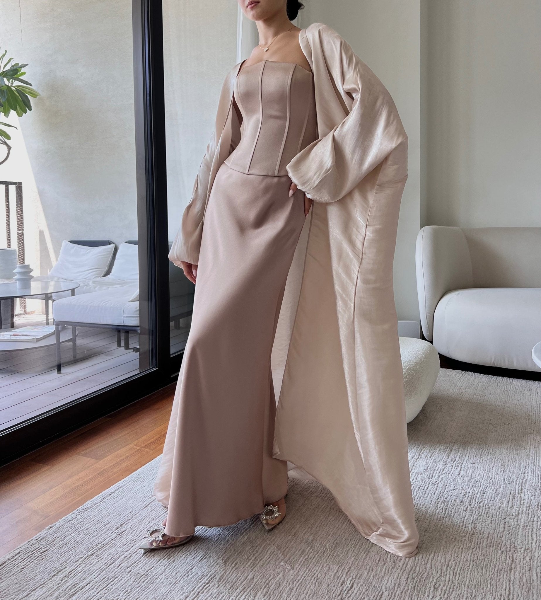 The model is wearing a rosy pink Aerin Abaya on top of the Silky Regina Corset set presenting a refined and fashionable appearance with a touch of elegance.