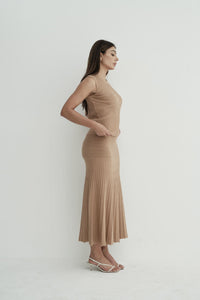 Model wearing Andrea Set, featuring a ribbed sleeveless top and a matching pleated midi skirt, styled with white strappy sandals, posing against a white background