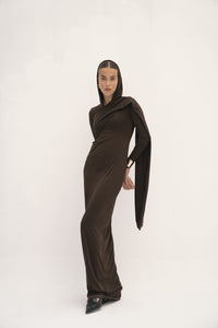 This dress has a sleek, fitted design in a dark, earthy tone with long sleeves and an attached drape that can be wrapped around the head, creating a sophisticated and modest look. The fabric appears smooth, with a slightly matte finish, and the overall silhouette is elongated and elegant. 
