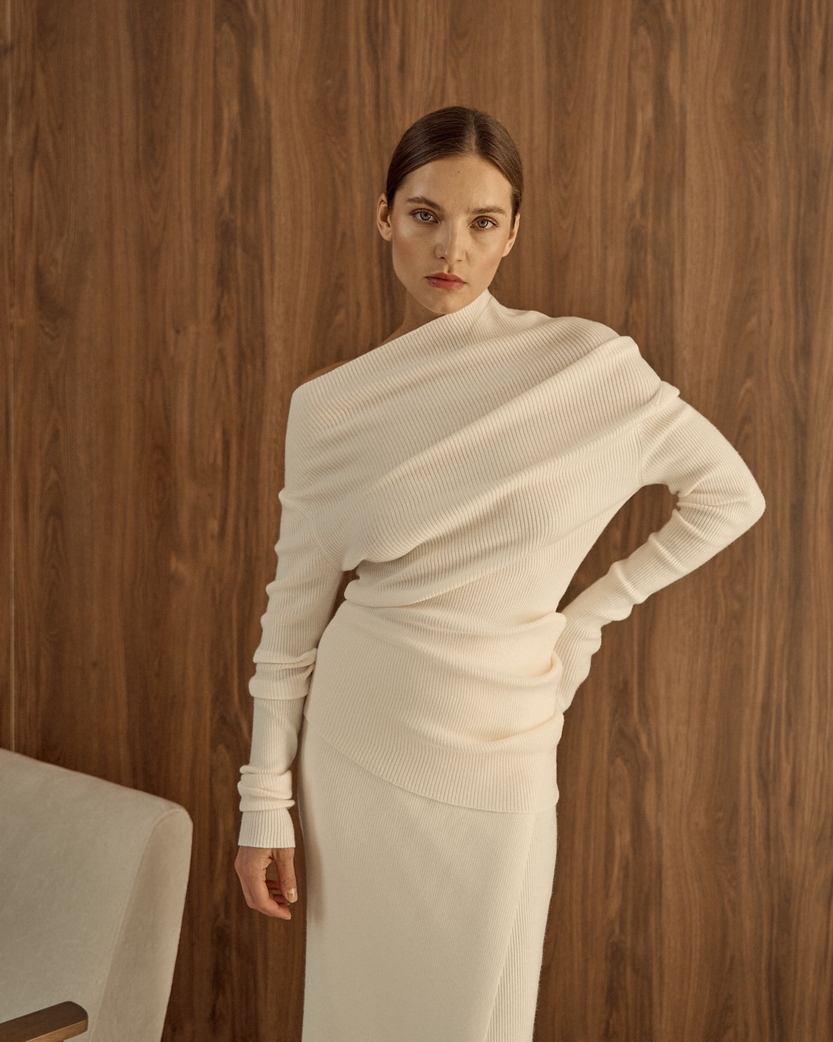 Avani Set in a creamy off-white ribbed knit fabric. The outfit features a long-sleeve asymmetrical draped top paired with a sleek matching skirt, minimalist, elegant aesthetic.