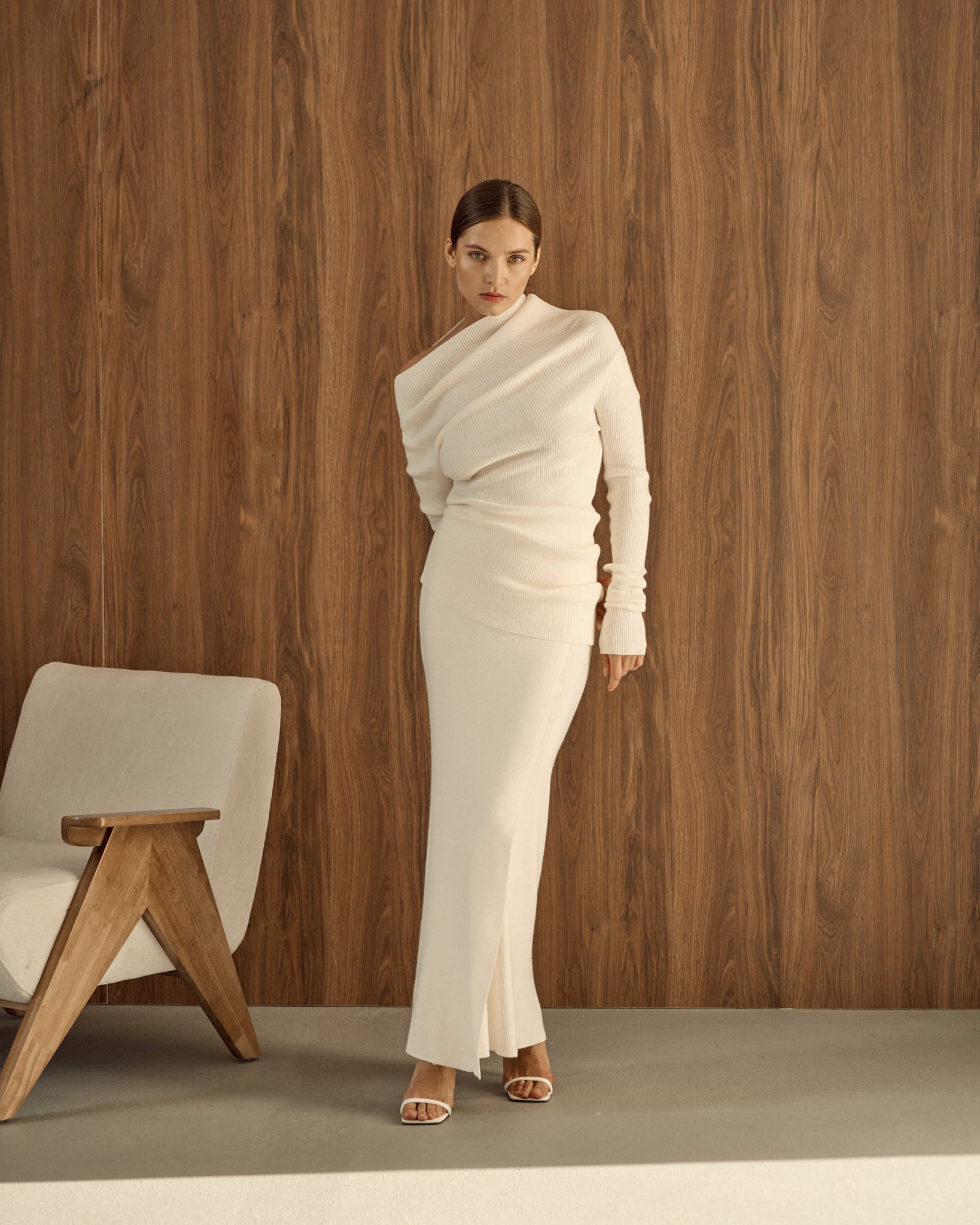 Avani Set in a creamy off-white ribbed knit fabric. The outfit features a long-sleeve asymmetrical draped top paired with a sleek matching skirt, minimalist, elegant aesthetic.