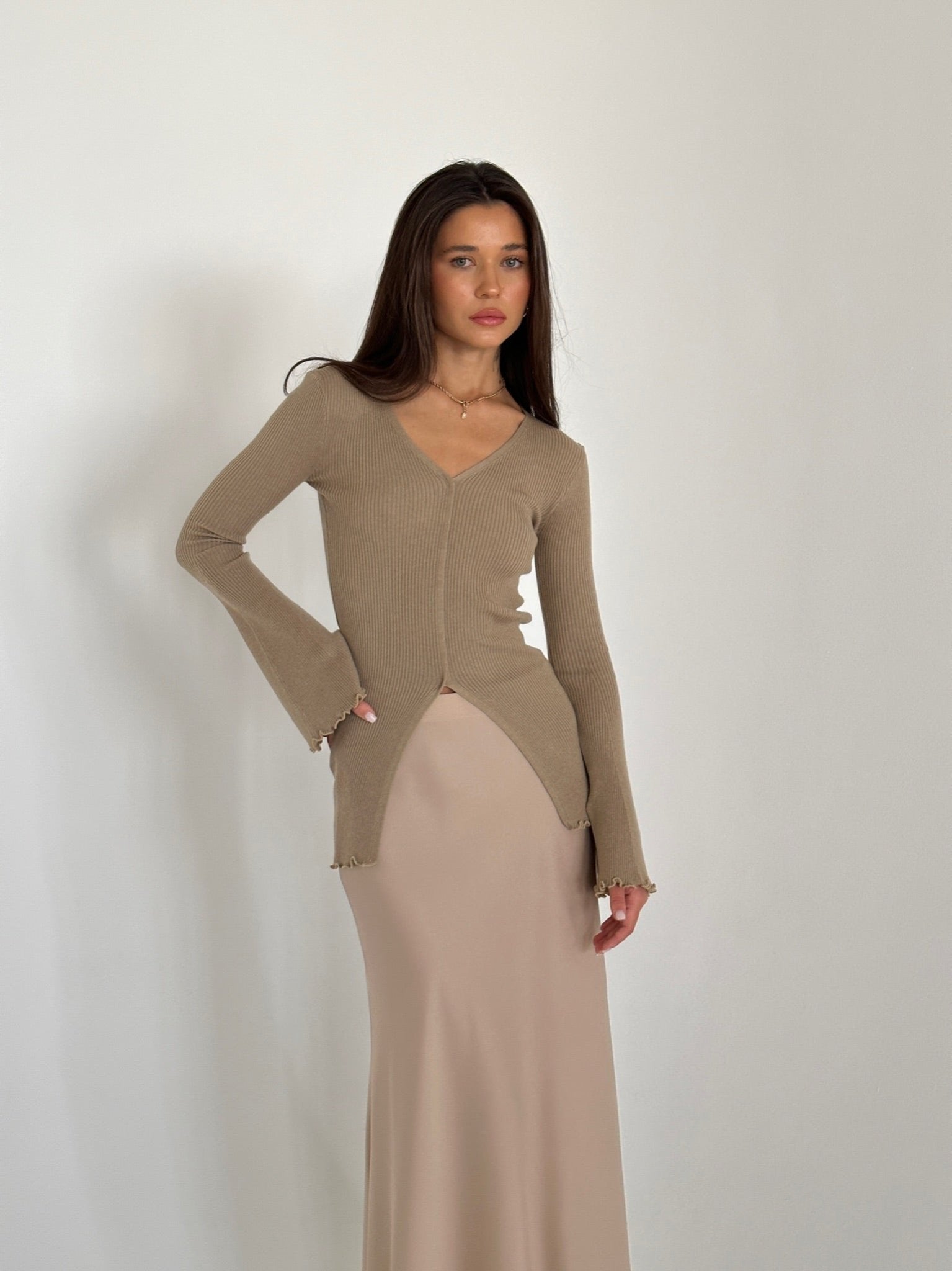 A woman in a flowing dress and heels, highlighting the Elara knit top, exuding grace and sophistication.