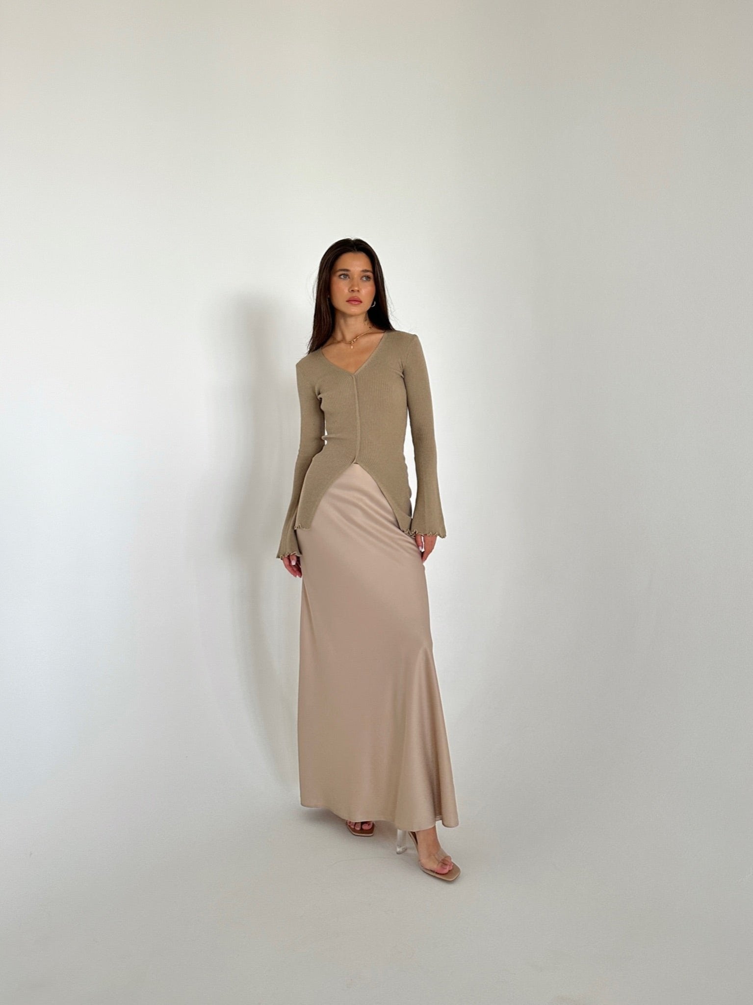 A woman in a flowing dress and heels, highlighting the Elara knit top, exuding grace and sophistication.