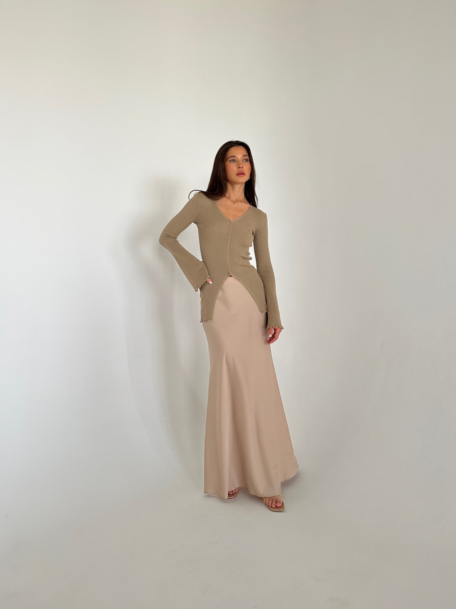 A woman in a flowing dress and heels, highlighting the Elara knit top, exuding grace and sophistication.