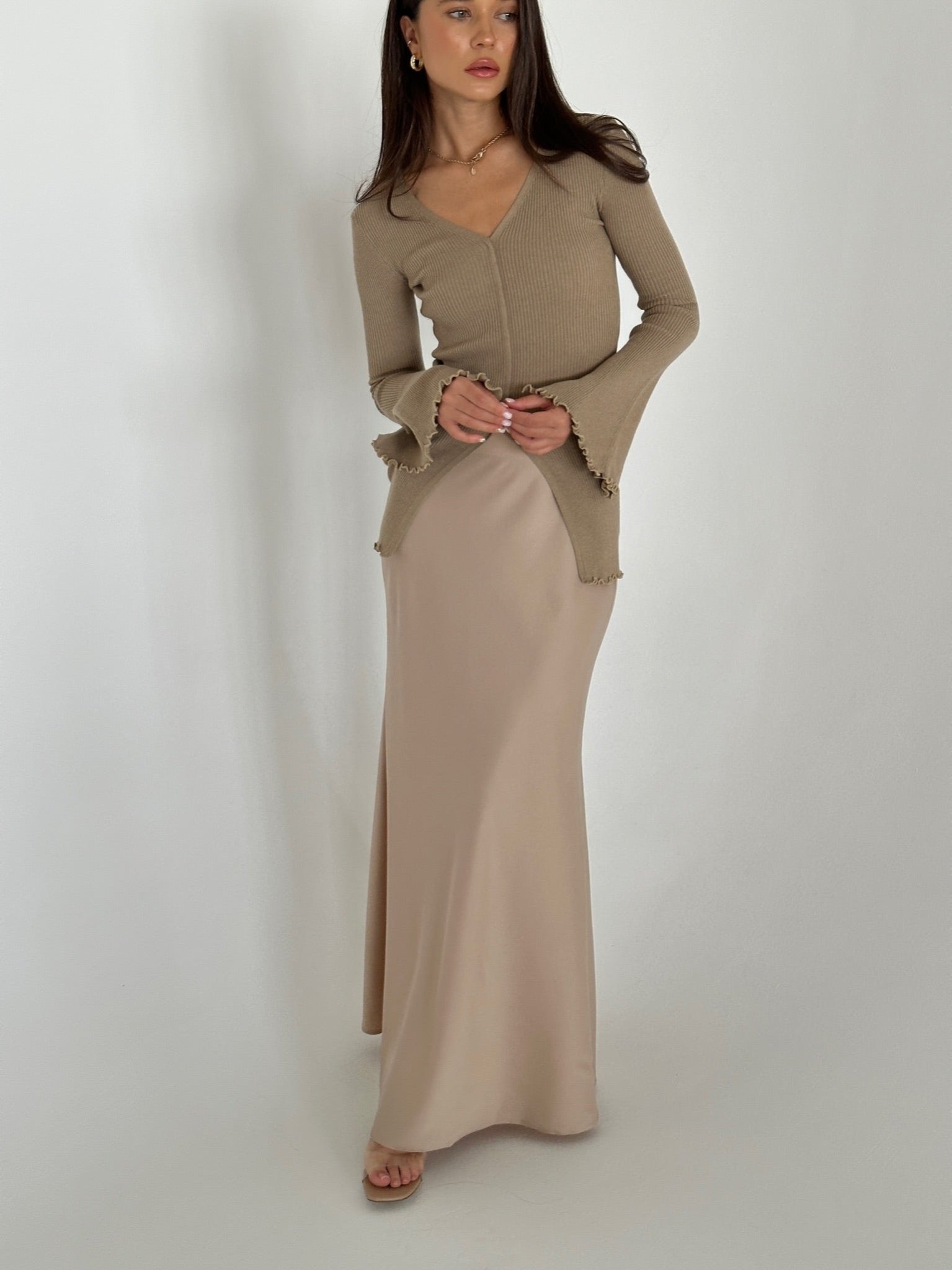 A woman in a flowing dress and heels, highlighting the Elara knit top, exuding grace and sophistication.