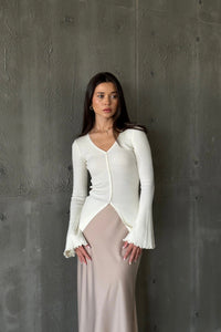 A woman models the Elara knit top, dressed in a white sweater and skirt, exuding sophistication and grace.