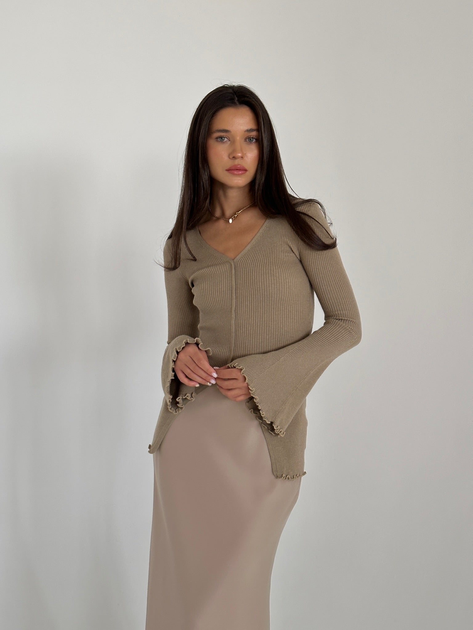 A woman in a flowing dress and heels, highlighting the Elara knit top, exuding grace and sophistication.