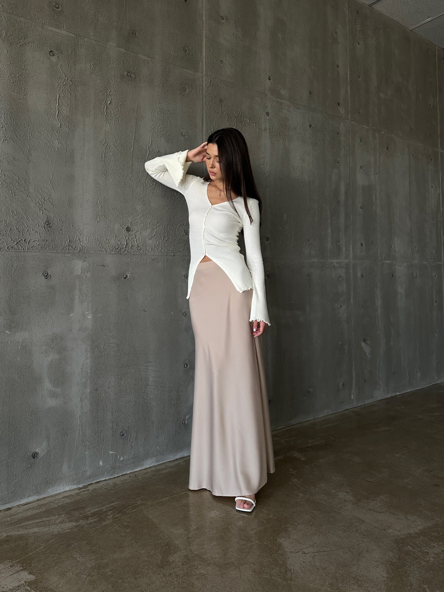 A woman models the Elara knit top, dressed in a white sweater and skirt, exuding sophistication and grace.