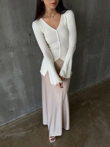 A woman models the Elara knit top, dressed in a white sweater and skirt, exuding sophistication and grace.