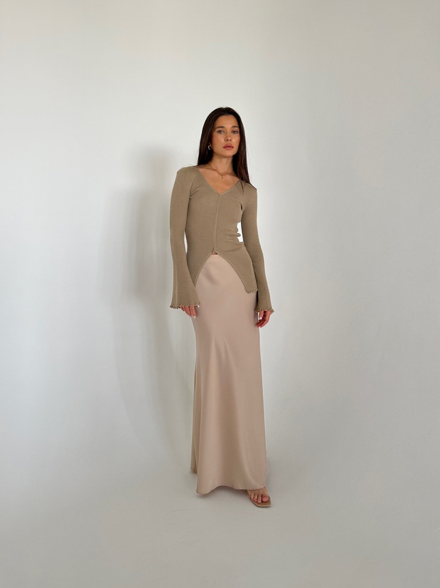 A woman in a flowing dress and heels, highlighting the Elara knit top, exuding grace and sophistication.