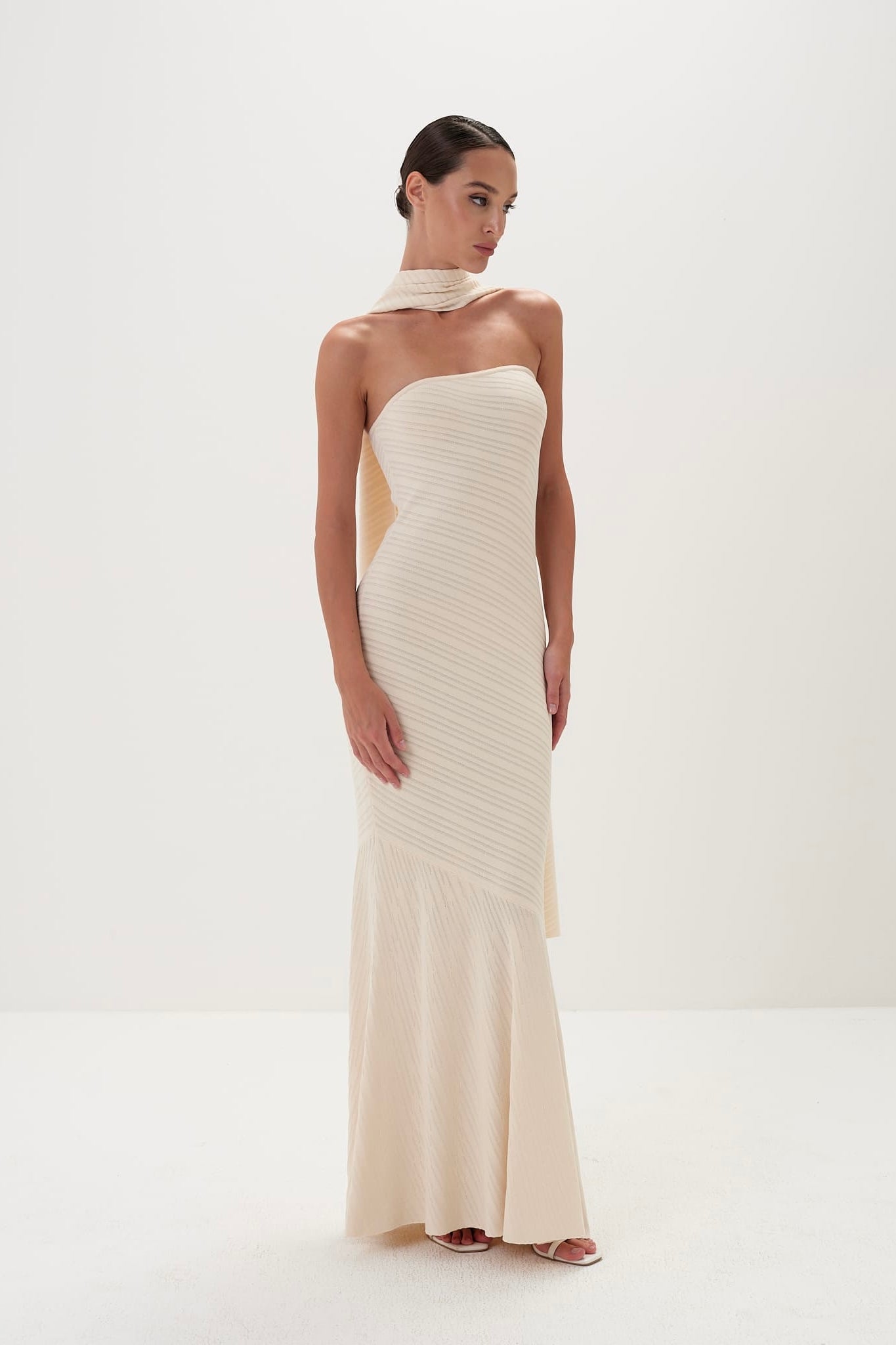Woman wearing a strapless, off-white evening gown on a white background