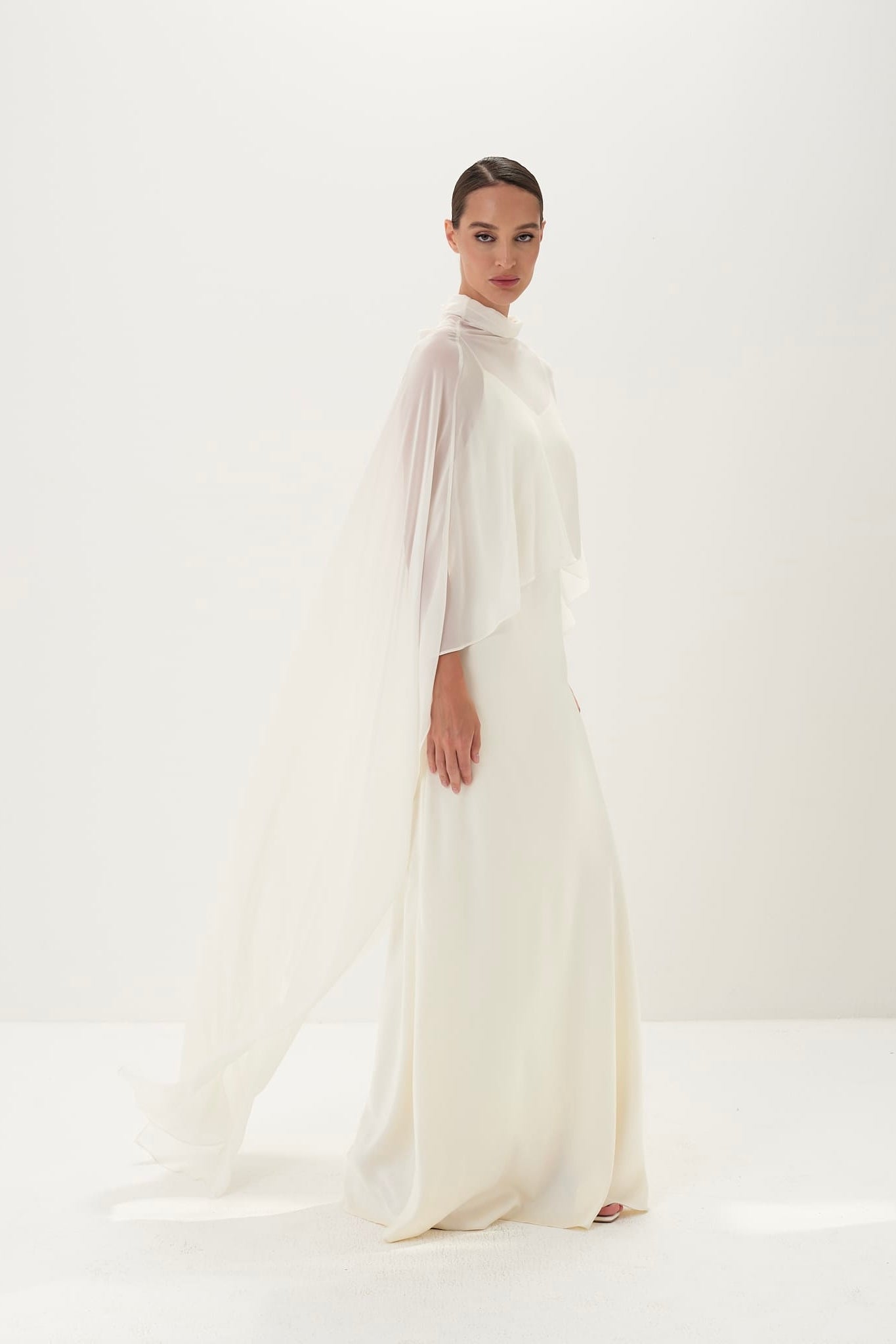 Woman wearing a long, light-colored dress against a white background