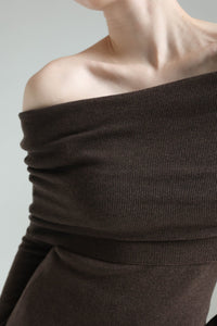 A person is shown from the neck down to the waist wearing the Madeline knit set in an off-shoulder chocolate brown design. The ribbed knitwear exudes timeless elegance, revealing the shoulders and collarbone against a plain light gray background.