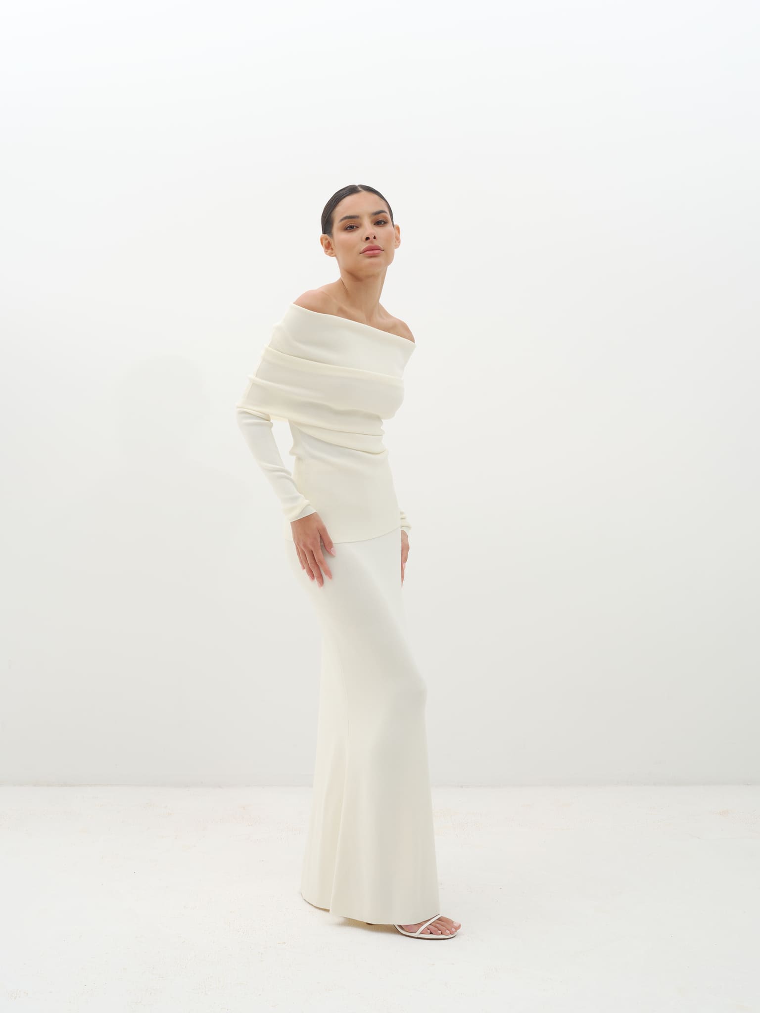 Woman wearing a white off-shoulder set against a white background