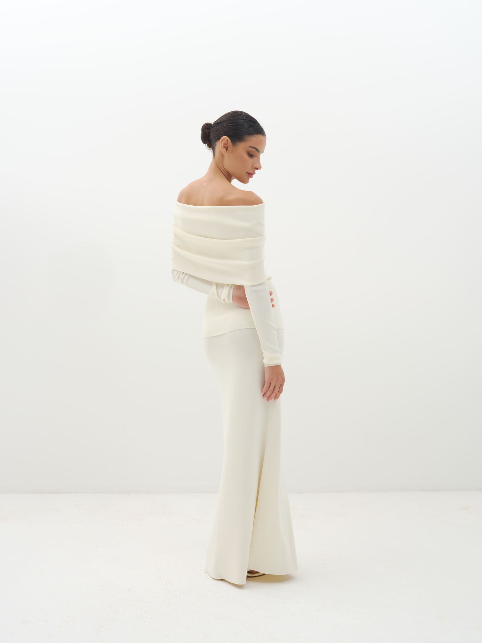Woman wearing a white off-shoulder set against a white background