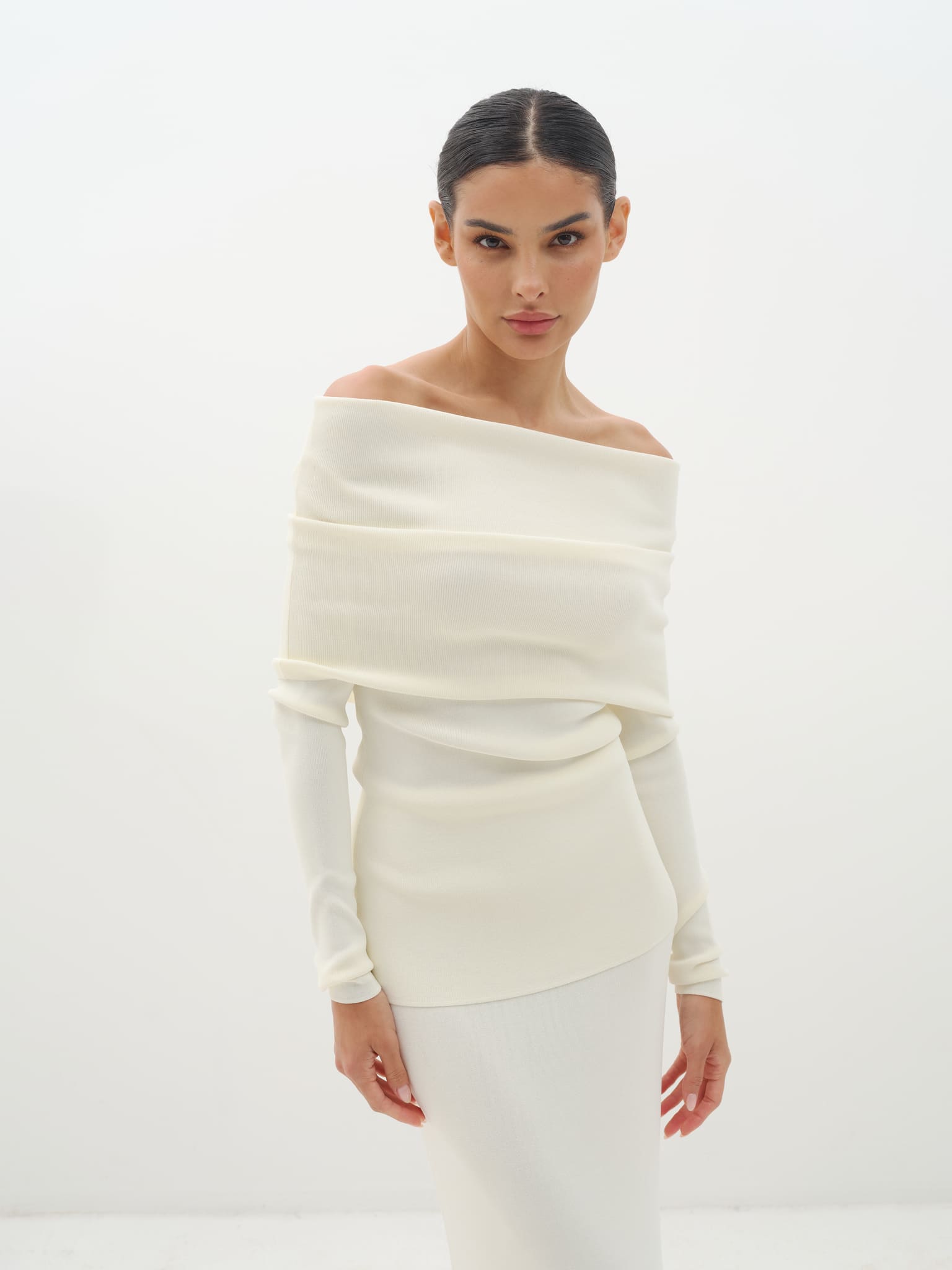 Woman wearing a white off-shoulder set against a white background