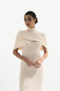 Woman wearing a white ribbed dress with a draped effect on a white background