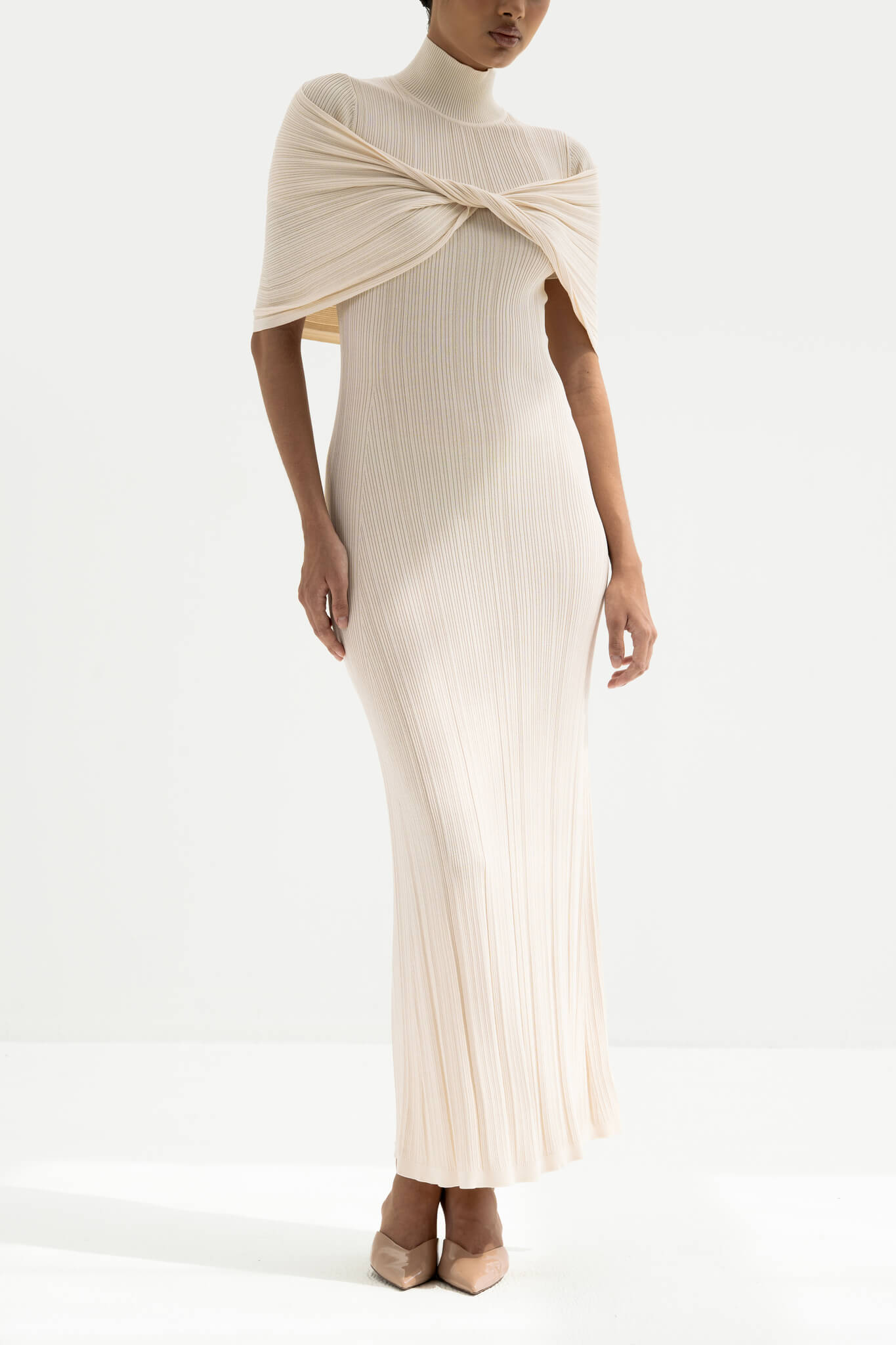 Woman wearing a white ribbed dress with a draped effect on a white background