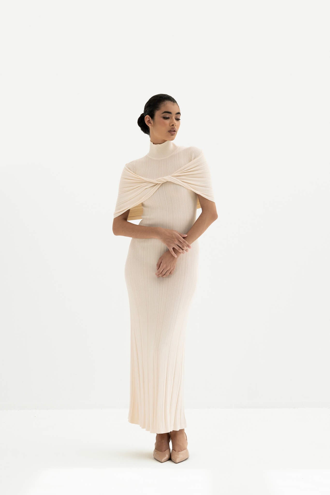 Woman wearing a white ribbed dress with a draped effect on a white background