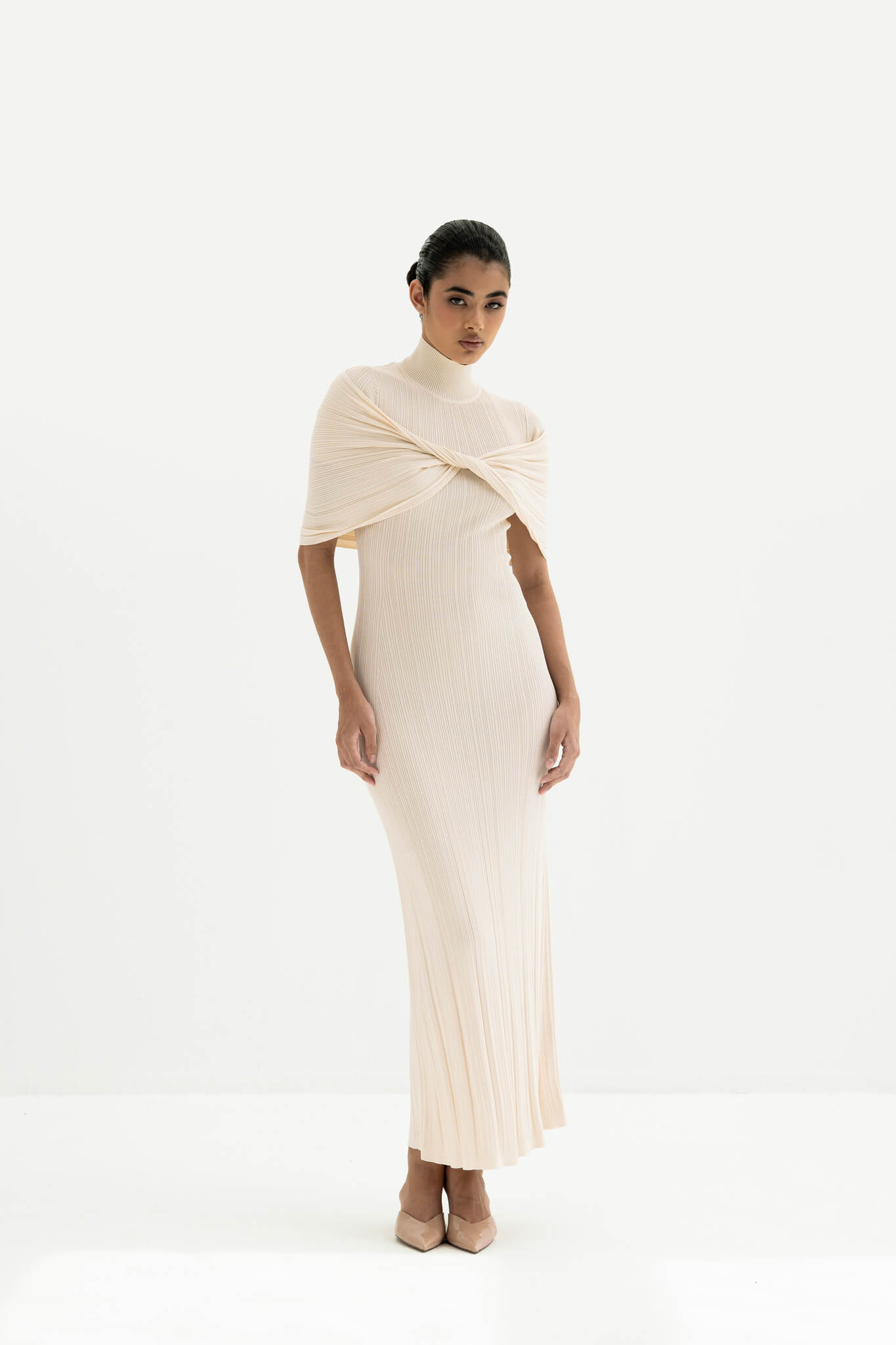 Woman wearing a white ribbed dress with a draped effect on a white background