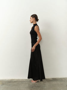 Sleek sleeveless black top featuring a high neck, fitted silhouette, and lightweight fabric, paired with a black satin skirt for a chic and minimalist aesthetic.