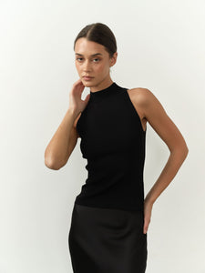 Sleek sleeveless black top featuring a high neck, fitted silhouette, and lightweight fabric, paired with a black satin skirt for a chic and minimalist aesthetic.